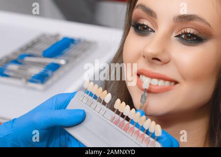 Giovane paziente sceglie il colore dei denti, la corona, l'impiallacciatura, il concetto di medicina, l'odontoiatria e la salubrità.il concetto di medicina, l'odontoiatria Foto Stock