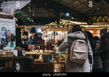 Londra, Regno Unito - 29 dicembre 2019: Persone in stallo alimentare nel mercato Spitalfields, una delle migliori strutture vittoriane del mercato di Londra con bancarelle che offrono f Foto Stock