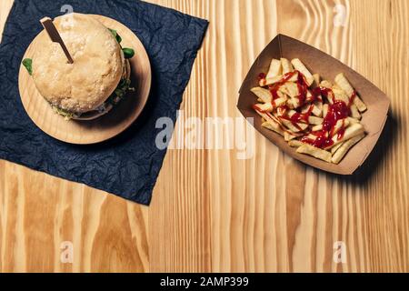vista dall'alto di un hamburger vegetariano gourmet su un tavolo in legno con patatine fritte con ketchup in un vassoio di cartone, cibo sano e stile di vita gastronomico Foto Stock