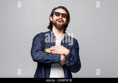 Giovane bell'uomo con barba su sfondo bianco isolato con occhiali 3d e tenendo un grande secchio di pop-corns Foto Stock