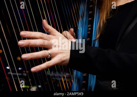 Immagine ravvicinata di una donna che gioca un arpa con multicolore in fibra ottica integrato luci nelle stringhe. Foto Stock