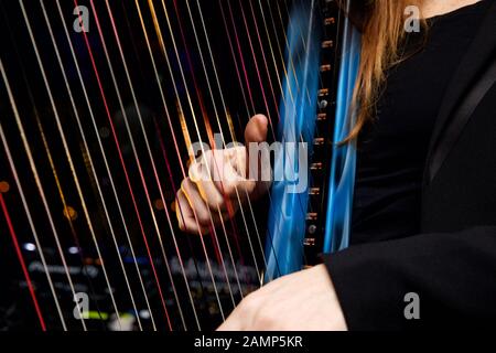 Immagine ravvicinata di una donna che gioca un arpa con multicolore in fibra ottica integrato luci nelle stringhe. Foto Stock