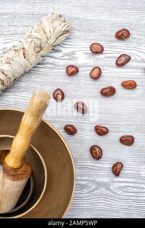 Piano di composizione dei laici di rune pietre, essiccata bianca salvia, incenso e campane tibetane su uno sfondo di legno Foto Stock