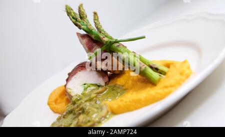 Un ristorante piatto principale di pollo avvolto nel prosciutto di Parma è servito con asparagi, funghi e dolce purea di patate. Foto Stock