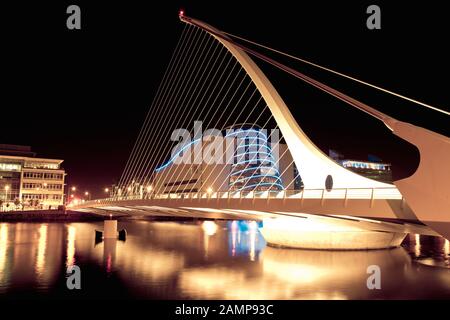 Esposizione lenta night shot di Samuel Beckett ponte sopra il fiume Liffey a Dublino, Irlanda. Il centro congressi può essere visto in background. Foto Stock