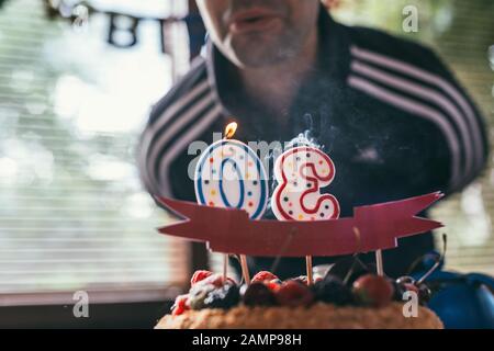 il ragazzo di compleanno soffia fuori le candele nella forma di 30 sulla torta di compleanno del blackberry di lamponi. Macro shot con messa a fuoco selettiva con DOF poco profondo. Foto Stock