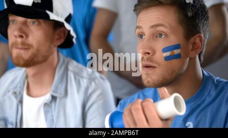 Appassionati di calcio argentini che guardano insieme la partita finale in pub, speranza di vittoria Foto Stock