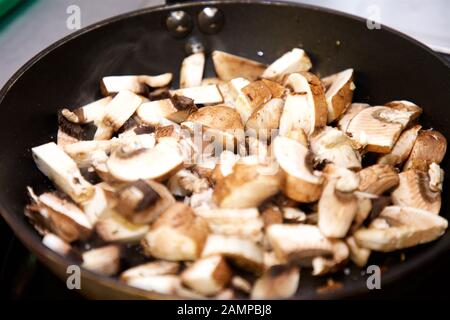 Sautéing funghi in padella. Foto Stock