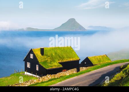 Mattinata nebbiosa vista di una casa con il tipico turf-top tetto di erba nel villaggio Velbastadur sull isola di Streymoy, isole Faerøer, Danimarca. Fotografia di paesaggi Foto Stock