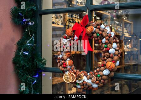 Tradizionale corona di Natale da noci, tangerini, cannella e arco rosso appeso su sfondo porta di legno Foto Stock