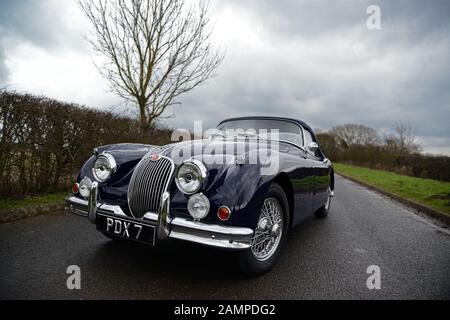 Jaguar XK150 parcheggiata su una corsia di campagna in un giorno d'inverno Foto Stock