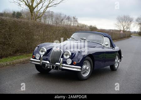 Jaguar XK150 parcheggiata su una corsia di campagna in un giorno d'inverno Foto Stock