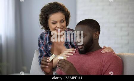 Uomo nero eccitato che guarda la scatola regalo da amata moglie, piacevole sorpresa Foto Stock