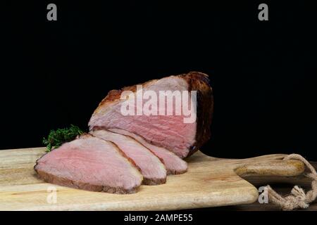 Primo piano di una giuntura di succosa roast beef irlandese affettato su un piatto di legno. Foto Stock