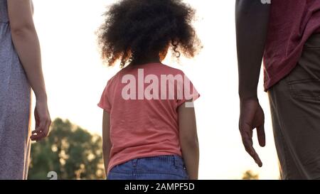 Piccola ragazza adottò stare tra due nuovi genitori, impaurito ad amare e a fidarsi Foto Stock