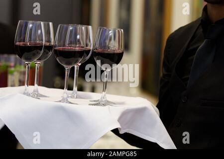 Un cameriere che serve di bicchieri di vino rosso su un vassoio. Foto Stock