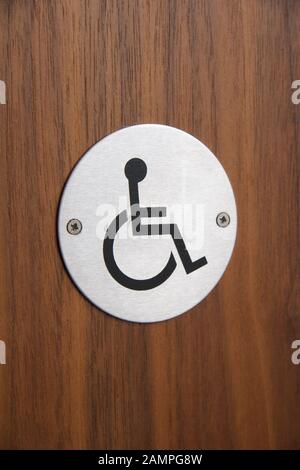 Cartello per disabili su una porta per servizi igienici in un edificio pubblico. Foto Stock