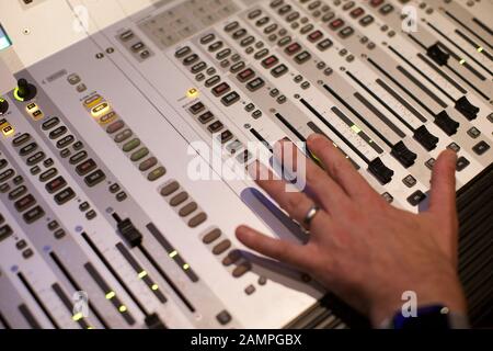 Close-up di un tecnico la mano spostando un fader switch su un broadcast console di miscelazione Foto Stock