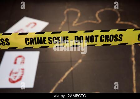 Simulazione della scena del crimine giallo con cordone di polizia di nastro e chalk contorno corpo. Foto Stock