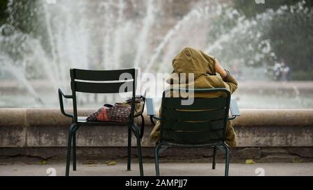 Donna si siede sulla sedia vicino alla fontana, il turista ha problemi con la dimora in ostello Foto Stock