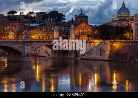 Immagine notturna della Basilica di San Pietro da Ponte Sant'Angelo e il fiume Tevere a Roma - Italia. Foto Stock