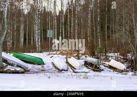 La barca capovolta che si trova sulla riva del lago ghiacciato Tuomiojarvi a Jyvaskyla in Finlandia. Foto Stock