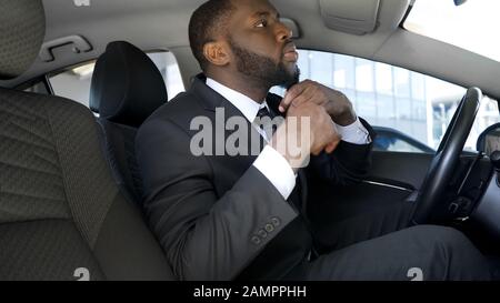 Bell'uomo nero in abito da lavoro che guarda in specchio per auto, pronto per la data Foto Stock