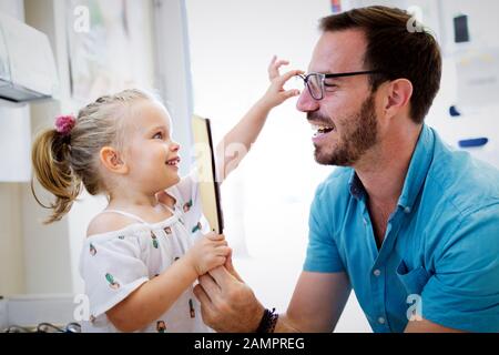 La cura della salute, la vista e il concetto di visione. Bambina scelta di occhiali con padre al negozio di ottica Foto Stock