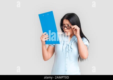Stile Libero. Donna asiatica in occhiali in piedi isolato su bianco con appunti di controllo rapporto interessato Foto Stock