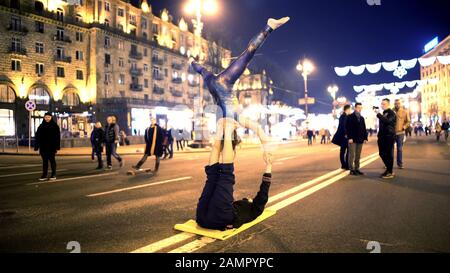 Giovane coppia che fa i trucchi pericolosi nel posto pubblico, spettacolo di yoga dell'acro Foto Stock