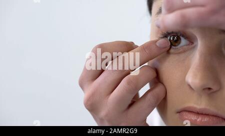 Giovane donna mettere lente a contatto in occhio, vista e igiene, viso closeup Foto Stock