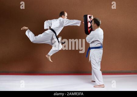 Con una cintura nera, un atleta addestra un colpo con la sua mano in un salto sul simulatore Foto Stock