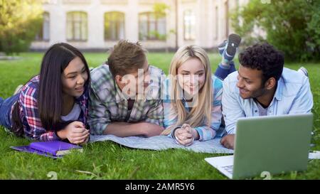 Gli amici multirazziali che guardano e ridono il video sul laptop, gli studenti in pausa Foto Stock