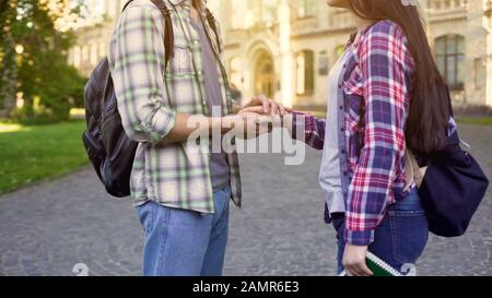 Giovane che tiene la mano della ragazza teneramente, amore dello studente, riunione sul freno Foto Stock