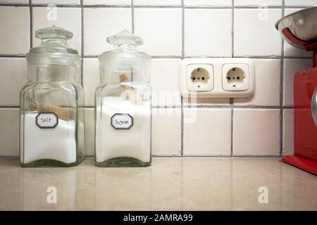 Nostalgico ancora vita di cucina retrò con due vasi di sale e zucchero sul bancone, fuoco selettivo sul sale. Foto Stock