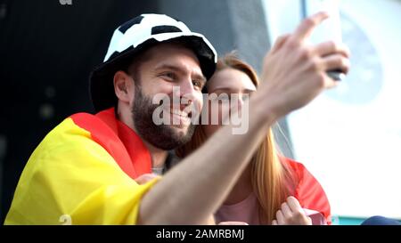 Appassionati di calcio attivi che si divertono e fanno selfie sui sedili dello stadio, tifosi Foto Stock