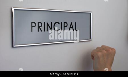 Porta principale ufficio, mano che bussa closeup, visita al capo del college, istruzione Foto Stock