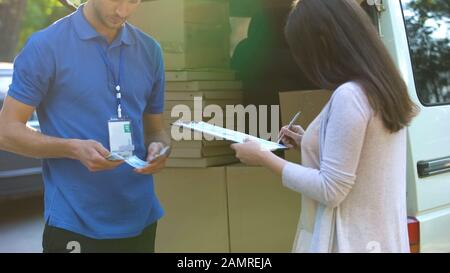 L'uomo di consegna contando i soldi mentre il cliente femminile firma il modulo circa ricevere Foto Stock