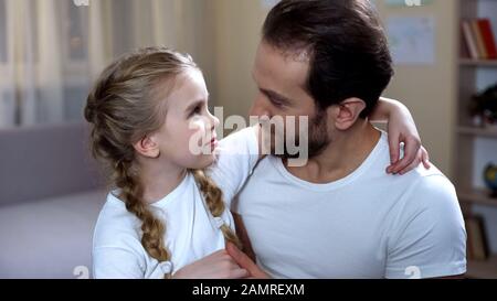 Il padre che si prende cura di cute figlia con amore e abbracciando, paternità felice Foto Stock