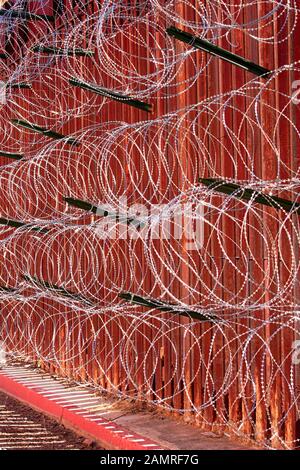 Il muro di confine tra USA e Messico con strati di filo di rasoio a Nogales AZ Foto Stock