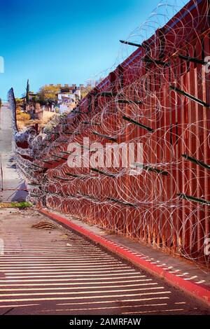 Il muro di confine tra USA e Messico con strati di filo di rasoio a Nogales AZ Foto Stock