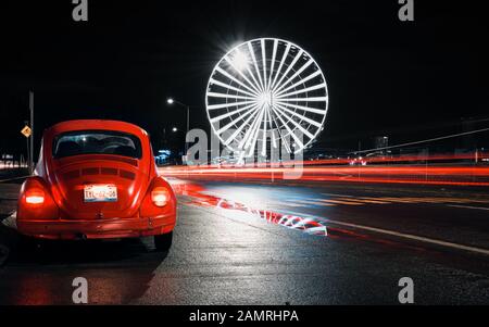 Angelolis, Puebla de Zaragoza, Messico, 15 ottobre 2018 - Foto di strada della vecchia auto Volkswagen Beetle con ruota panoramica gigante della città di Puebla di notte. Lunga esposizione della strada messicana. Foto Stock