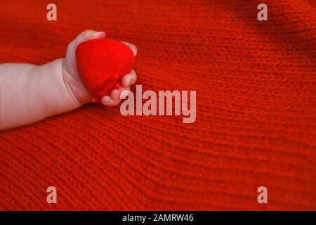 il bambino tiene il cuore rosso in mano. Neonato il giorno di San Valentino. Buona Festa Della Mamma. Spazio di copia. Foto Stock