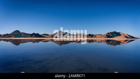 Le piste degli pneumatici sono visibili e le montagne si riflettono su un sottile strato d'acqua che copre le Bonneville Salt Flats in inverno vicino al Bonneville Speedway. Foto Stock