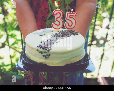 Donna che tiene una torta di compleanno 35th Foto Stock