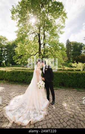 Lo sposo e la sposa in piedi dal grande albero nel parco Foto Stock