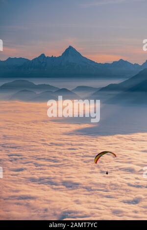 Silhouette di Un Parapendio che vola sopra moquette nube al tramonto, Gaisberg, Salisburgo, Austria Foto Stock