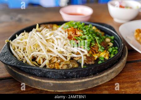 Frittata cinese croccante Oyster servire su piatto di ferro caldo in cima con germoglio di fagiolo fresco e tritare lo scalogno. Foto Stock