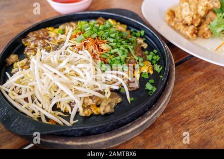 Frittata cinese croccante Oyster servire su piatto di ferro caldo in cima con germoglio di fagiolo fresco e tritare lo scalogno. Foto Stock