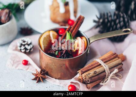 Primo piano di VIN brulé in una casseruola di rame accanto ad una torta di Natale con mirtilli rossi Foto Stock